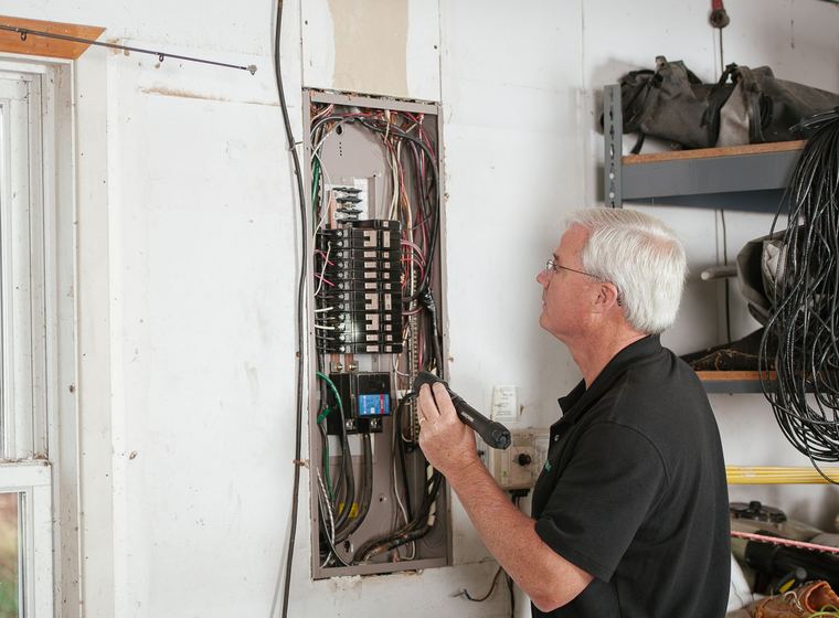 An electrician testing an open residential breaker panel
